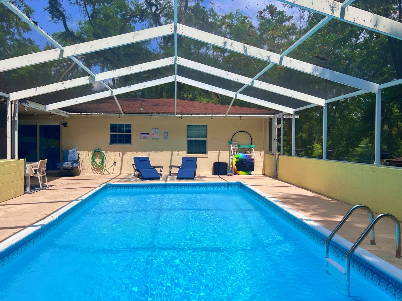 Screened pool with blue lounge chairs at Rosemary Retreat