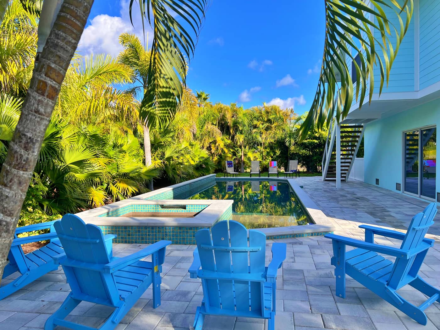 Backyard pool with blue lounge chairs among palms at SkyWater Retreat